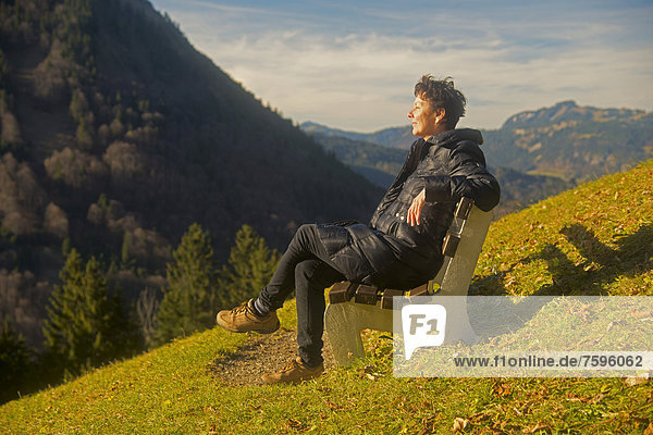 Frau sitzt entspannt auf einer Bank  Sonnenbad  Gerstruben bei Oberstdorf  Allgäu  Bayern  Deutschland  Europa  ÖffentlicherGrund