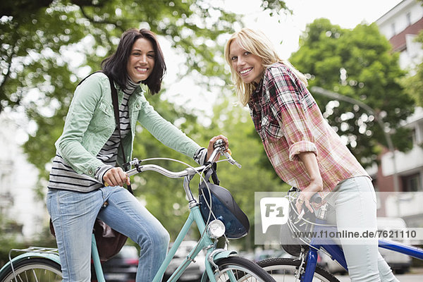 Frauen sitzen auf Fahrrädern auf der Stadtstraße