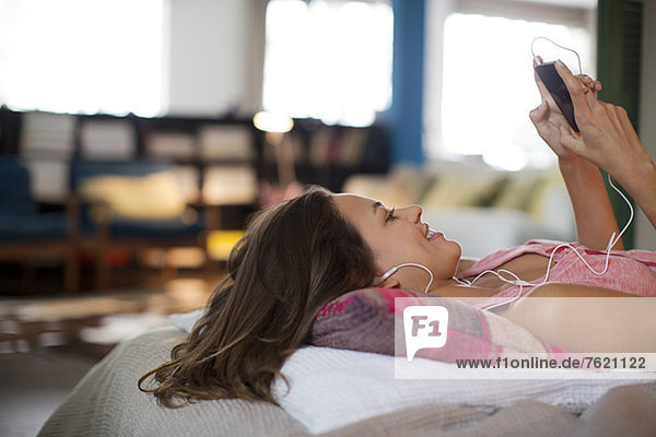 Woman listening to mp3 player on bed