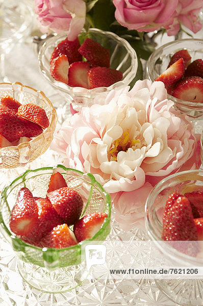Schalen mit Erdbeeren und Blumen auf dem Tisch