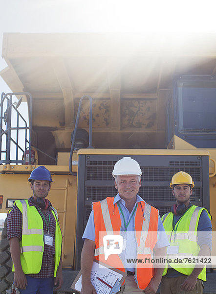 Businessman and workers by machinery on site