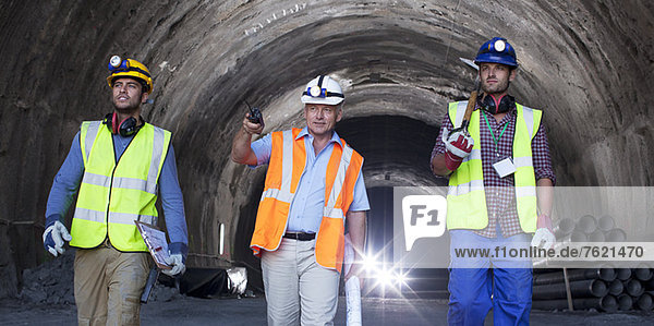 Geschäftsmann und Arbeiter  die im Tunnel spazieren gehen