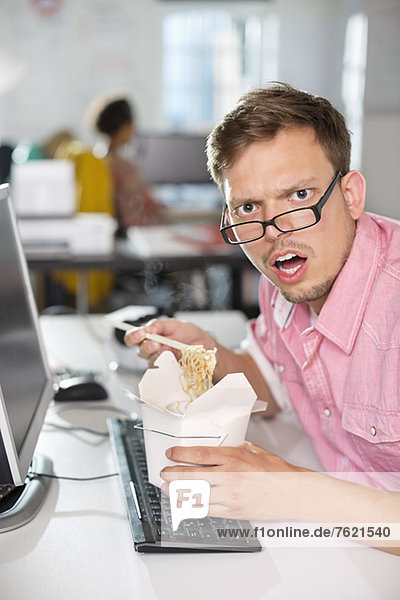 Businessman eating Chinese food at desk