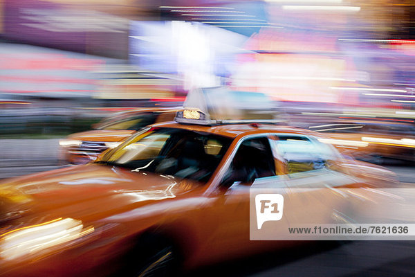 Blurred view of taxi on city street at night