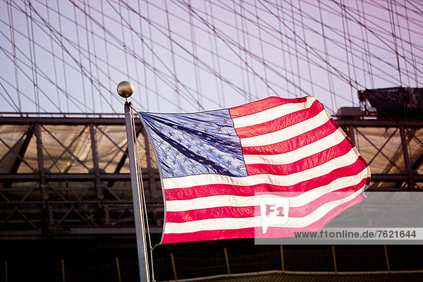 American flag waving by urban bridge