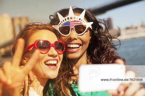 Women taking picture of themselves in novelty sunglasses