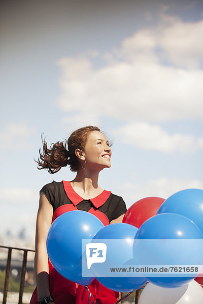 Frau trägt einen Haufen Luftballons.