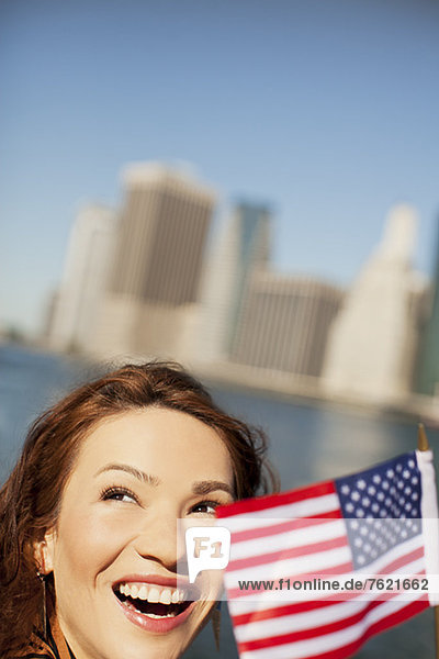 Woman waving American flag by city cityscape