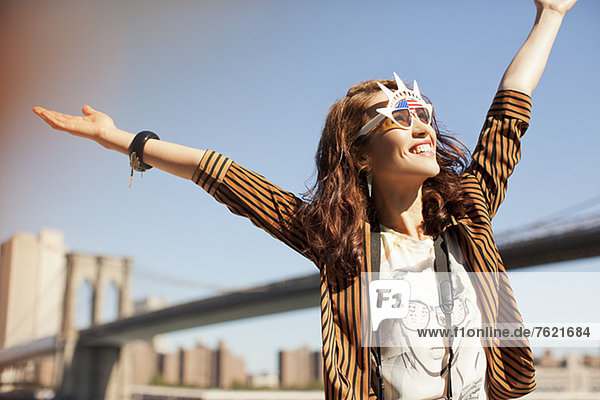 Woman in novelty sunglasses standing by urban bridge