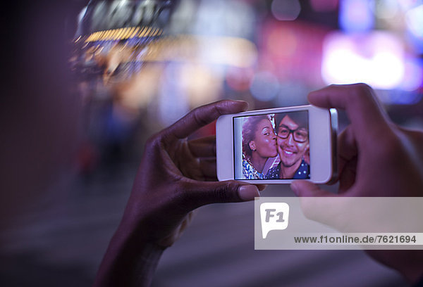 Frau hält Handy mit Foto auf dem Bildschirm