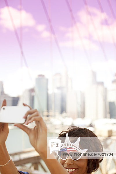 Woman in novelty sunglasses taking picture by city cityscape
