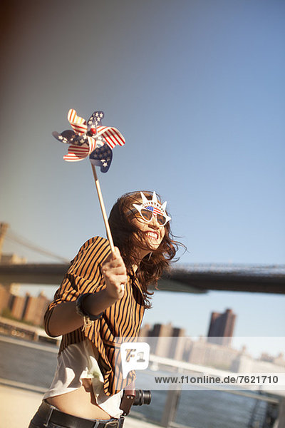 Woman with novelty sunglasses and pinwheel by city bridge