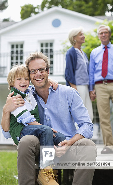 Father and son smiling outside house