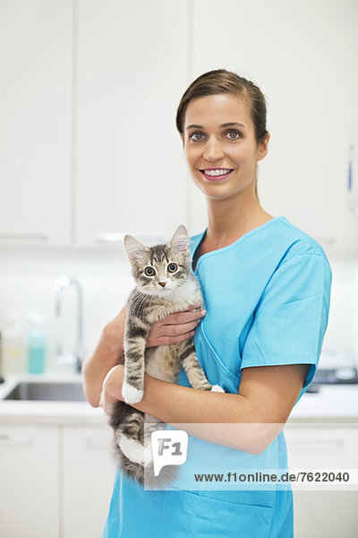 Lächelnder Tierarzt hält Katze in Tierarztpraxis