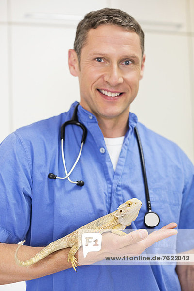 Lächelnder Tierarzt mit Eidechse in der Tierarztpraxis