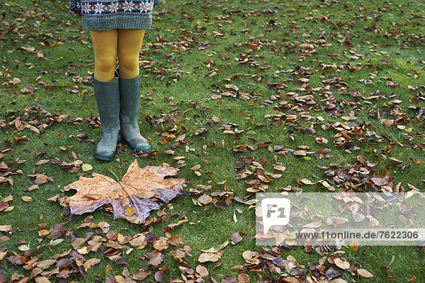Mädchen am großen Herbstblatt stehend