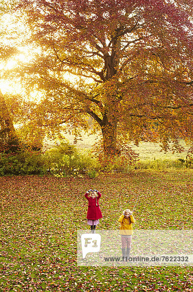 Mädchen spielen im Herbstlaubfeld