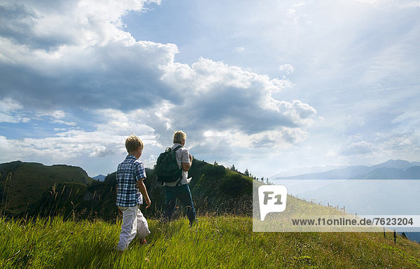 Father and son hiking on grassy hilltop