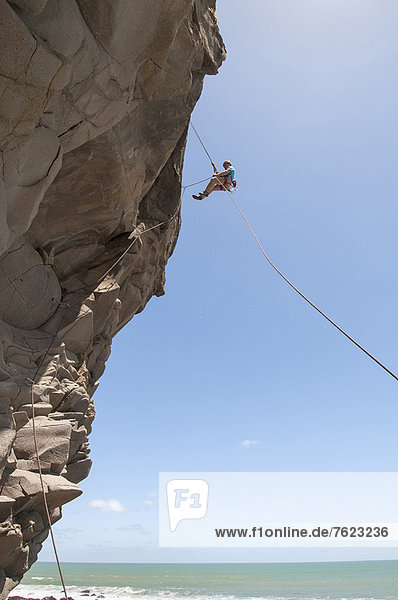 Rock climber abseiling jagged cliff