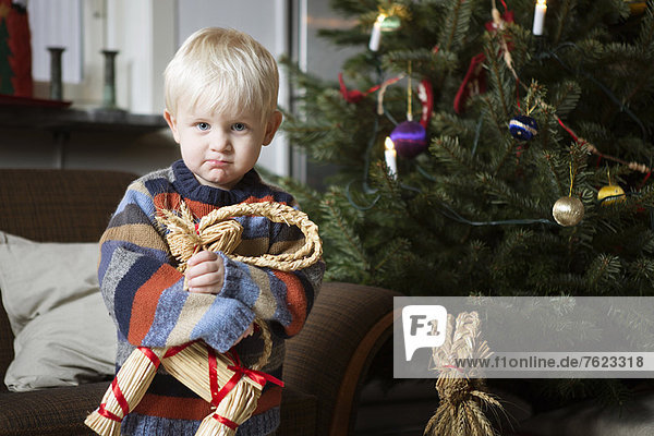 Boy holding toy by Christmas tree