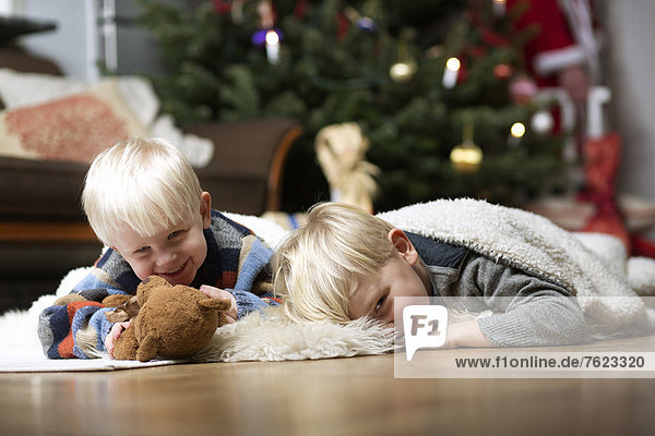 Jungen spielen auf dem Boden am Weihnachtsbaum