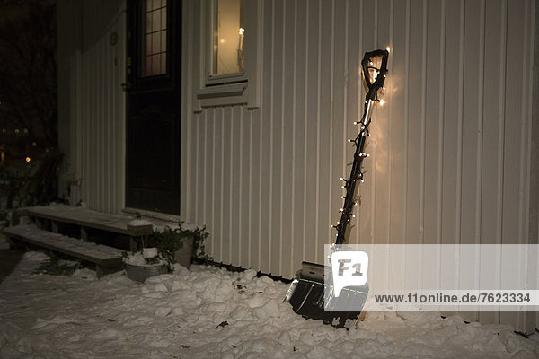 Schaufel mit Lichterkette im Schnee