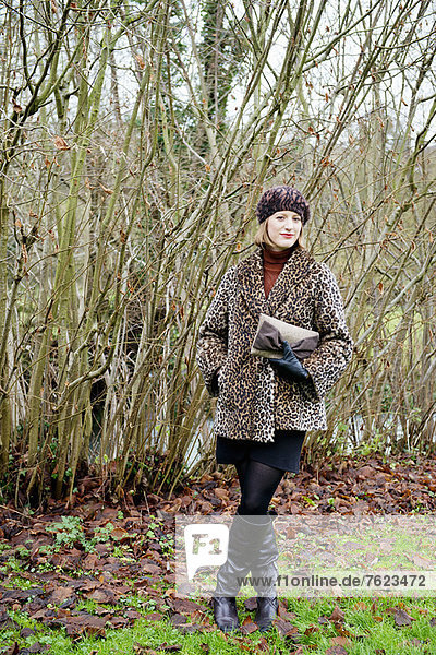 Lächelnde Frau im Wald stehend