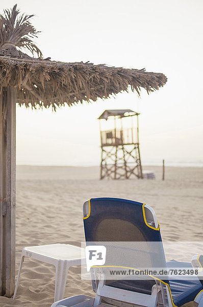 Liegestuhl und Sonnenschirm am Strand