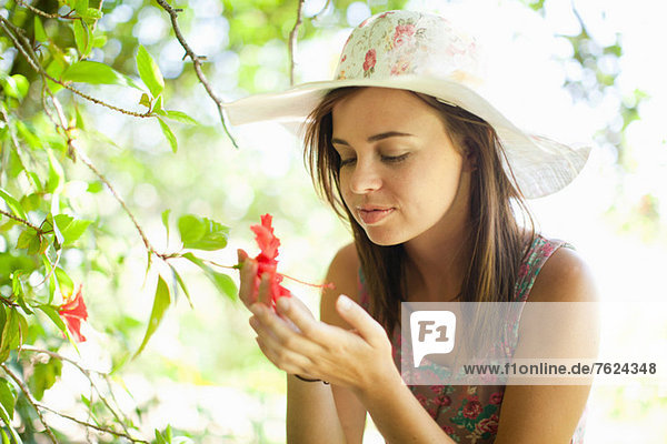 Frau bewundert Blume im Park