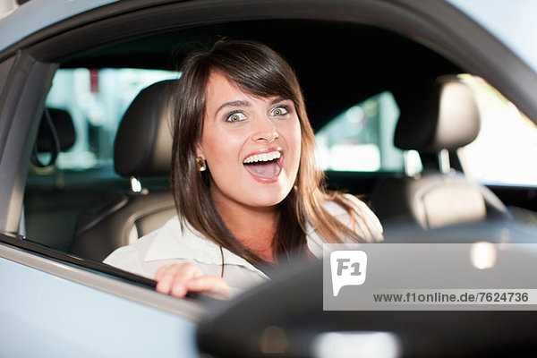 Excited woman sitting in car