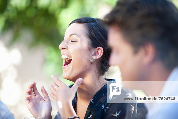 Woman laughing at table outdoors