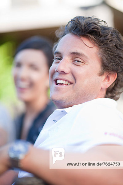 Smiling man sitting at table outdoors