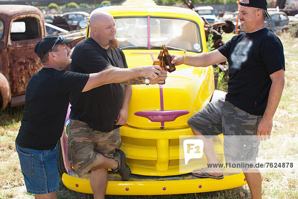 Men drinking beer by colorful car