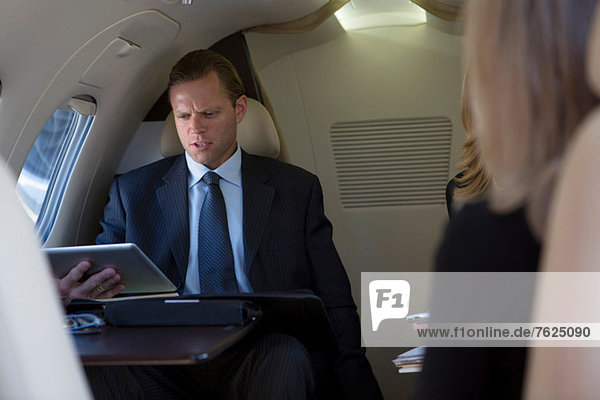 Geschäftsmann mit Tablette im Flugzeug