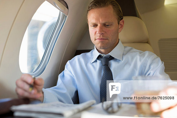 Businessman doing crossword on airplane
