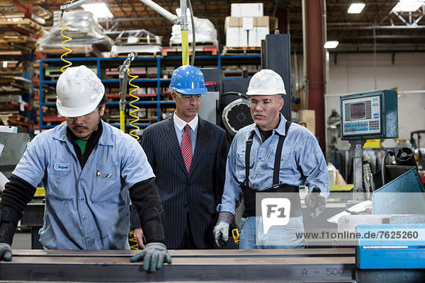 Workers and businessman in metal plant
