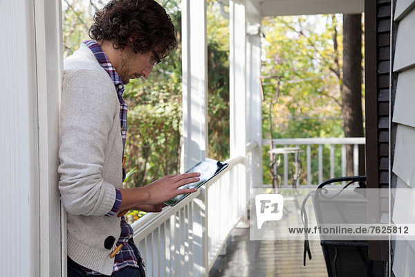 Mann mit Tablet-Computer auf der Veranda