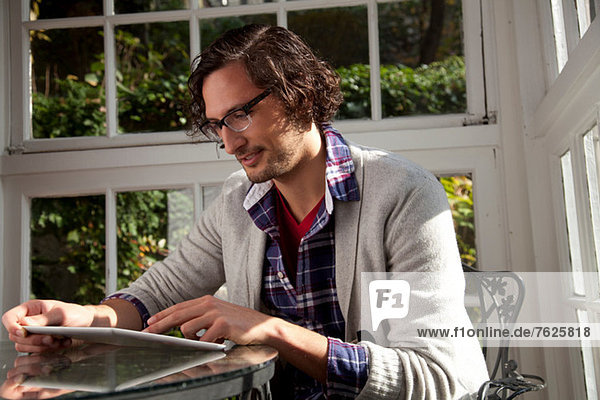 Mann mit Tablet-Computer am Tisch