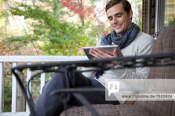 Man using tablet computer on porch
