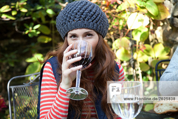 Woman drinking wine at table outdoors