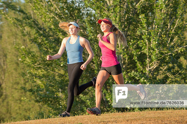 Teenager-Mädchen laufen zusammen im Feld.