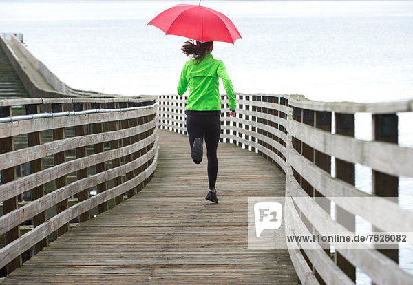 Woman running under umbrella