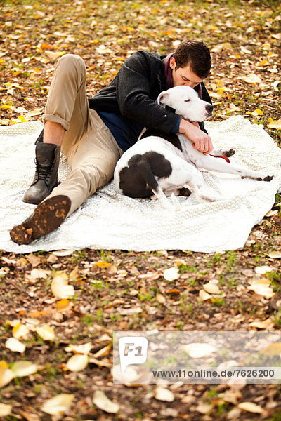 Mann und Hund entspannen auf Picknickdecke
