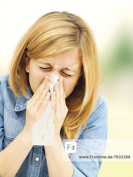 Junge Frau putzt sich die Nase  Schnupfen  Allergie