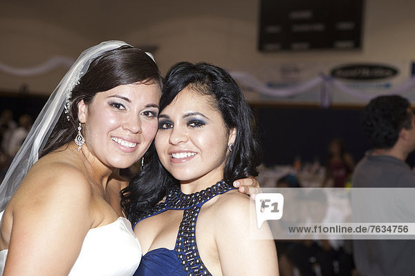 Hispanic bride hugging friend