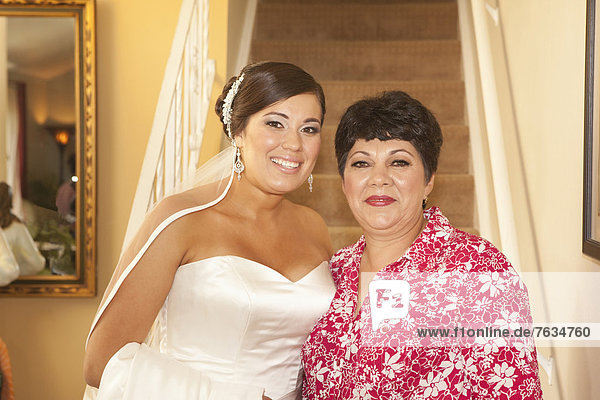 Hispanic bride standing with mother