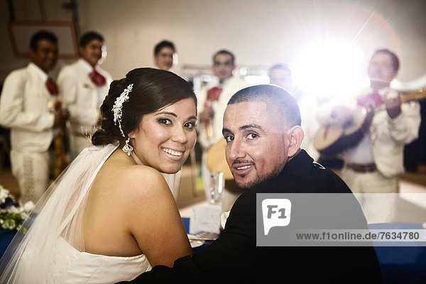 Hispanic bride and groom at wedding reception