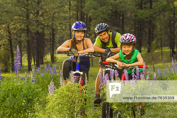 Family sitting on bicycles in meadow