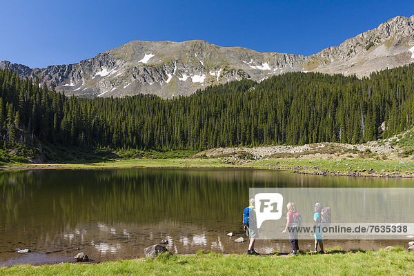 Hikers admiring still lake in rural landscape