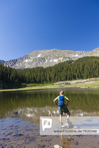 Caucasian hiker standing on rocks in lake
